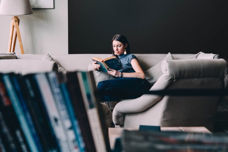 young,beautiful,woman,enjoys,reading,sitting,on,a,comfortable,couch.